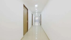 A long, narrow hallway with white walls and a shiny floor, leading to a door at the end. - Fabhotel Blest Inn (New Delhi)