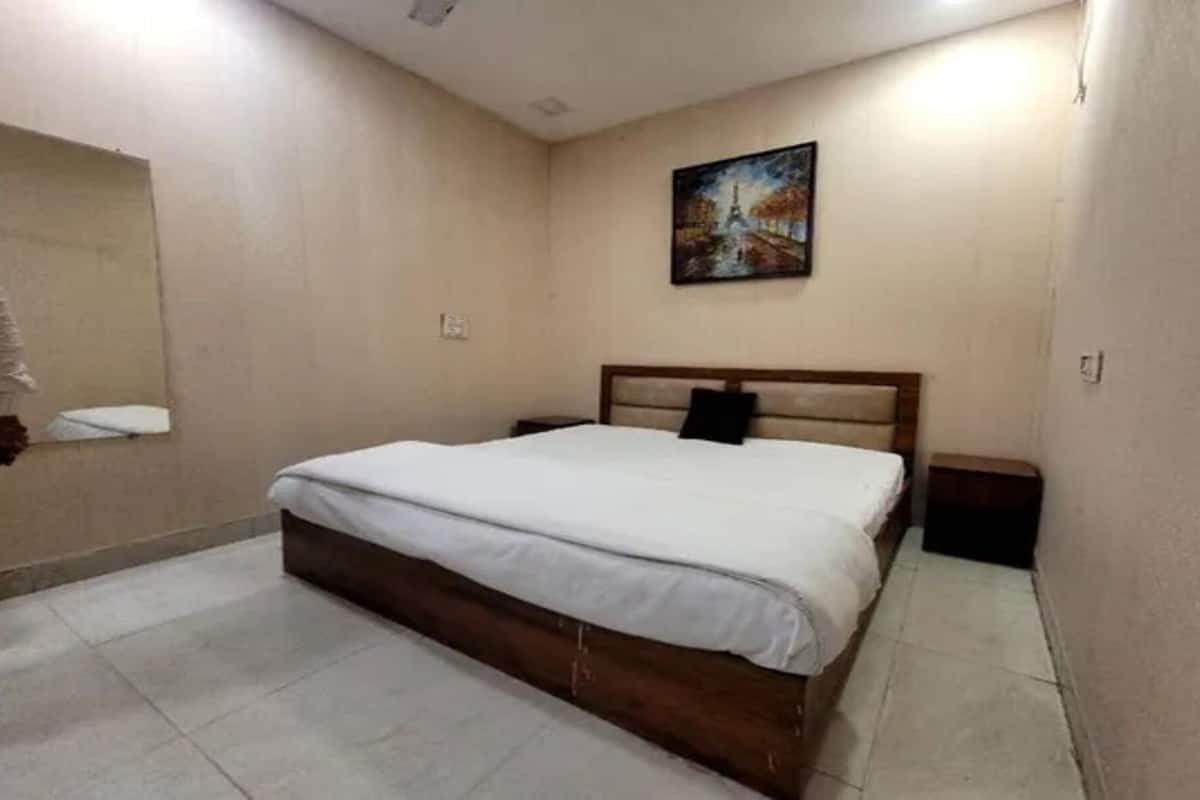 Un dormitorio con cama, mesita de noche, un cuadro colgado en la pared y un espejo de baño.