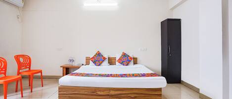 A hotel room with a bed, two chairs, a nightstand, and a wardrobe.