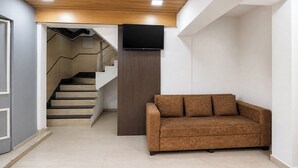 Un interior moderno con una escalera, un televisor de pantalla plana y un sofá marrón.