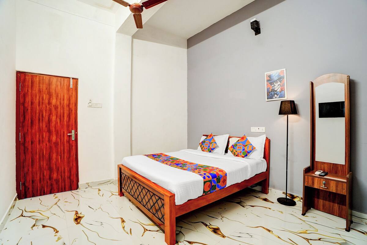 A bedroom with a wooden bed, a mirror, a floor lamp, and a door.