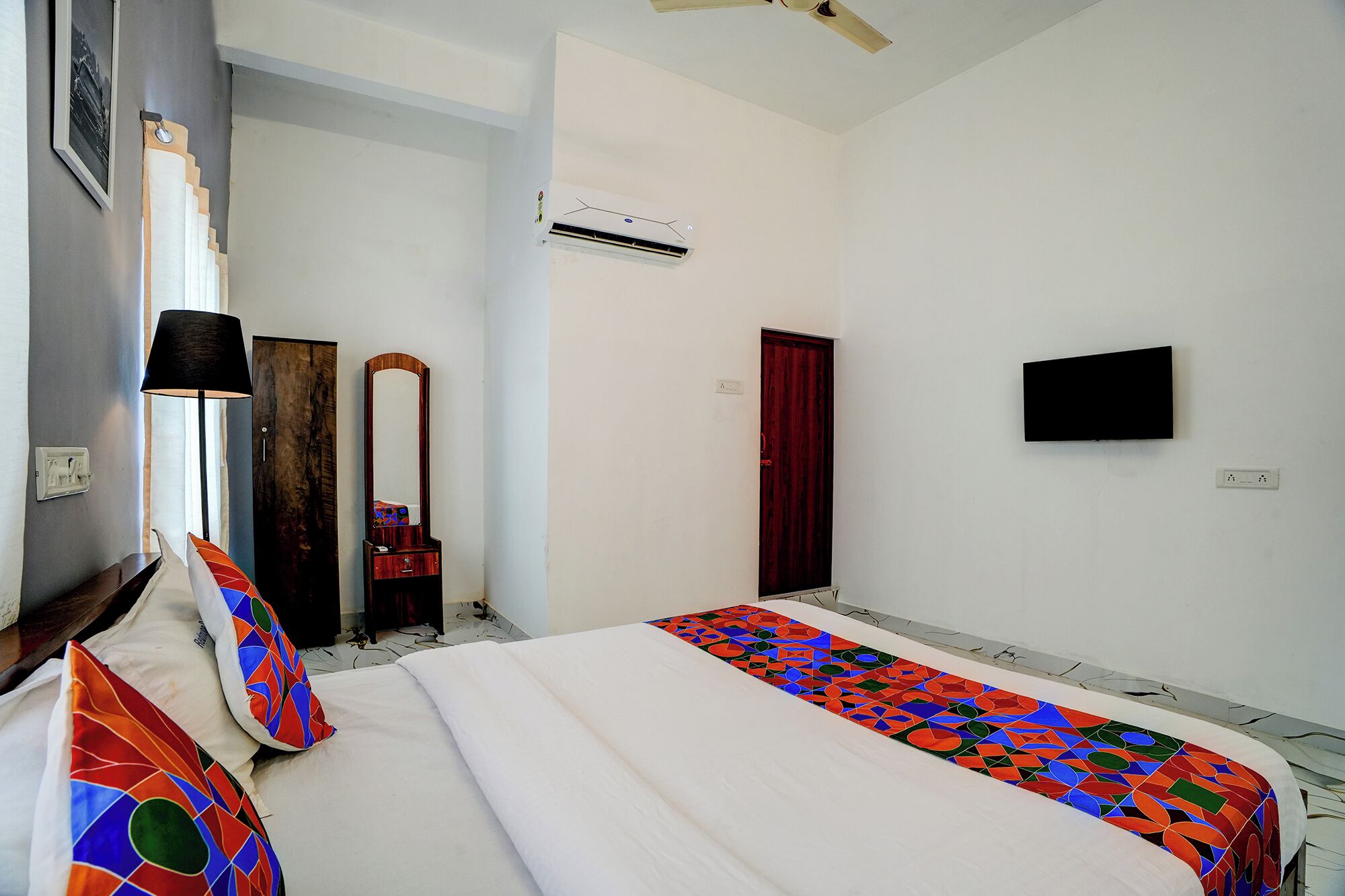Une chambre d’hôtel équipée d’un lit, d’un miroir, d’une armoire, d’un climatiseur, d’une porte et d’un téléviseur.