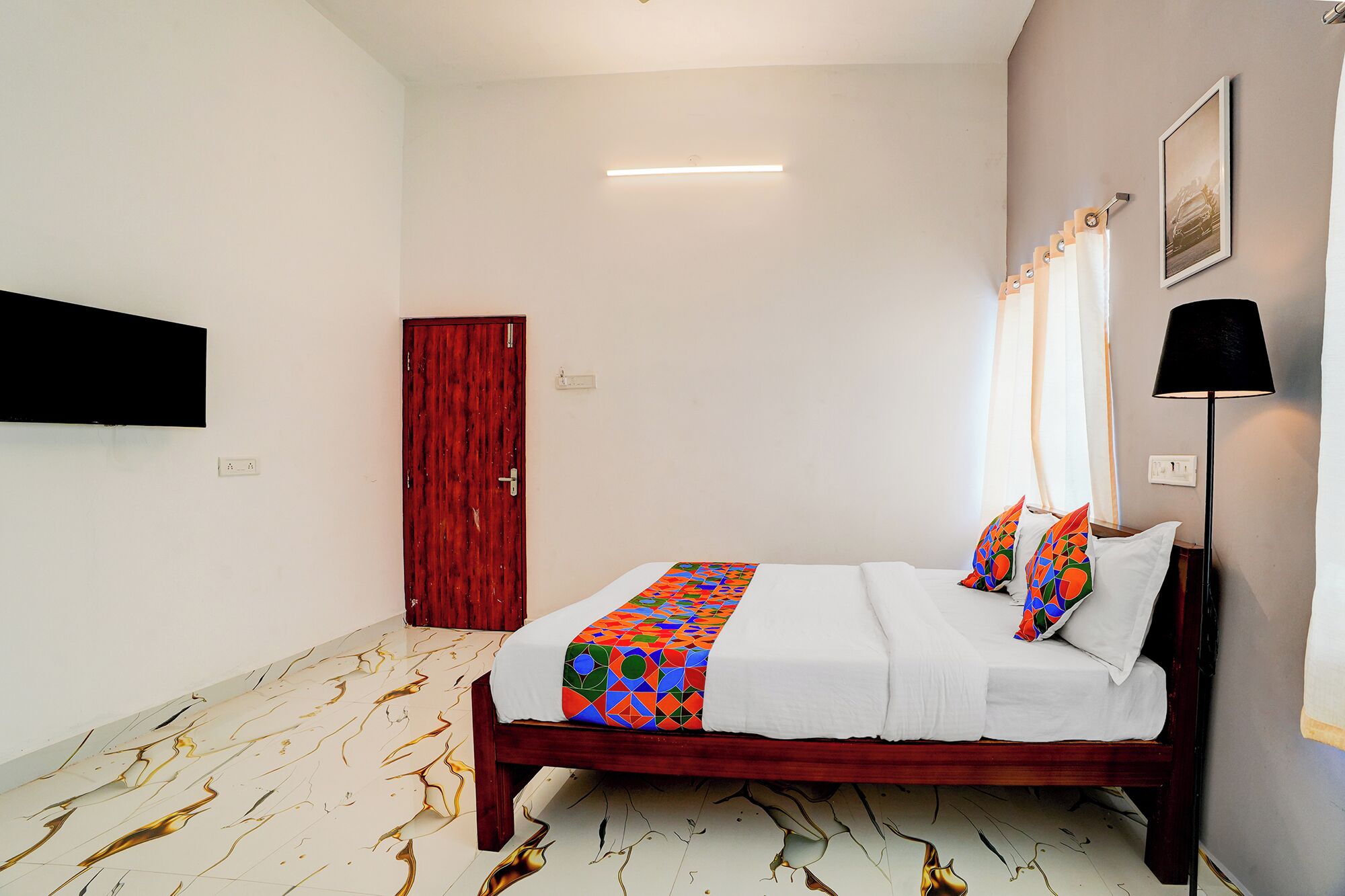 Une chambre à coucher avec un lit, une porte, un luminaire, un tableau accroché au mur et une lampe.