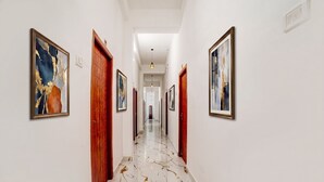 Un couloir aux murs blancs, orné de tableaux encadrés et doté d’un sol en marbre.