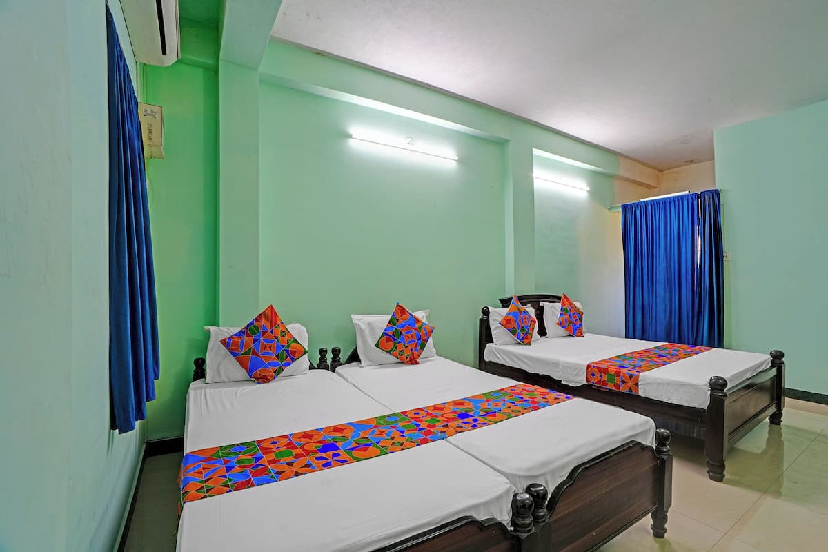 Habitación de hotel con dos camas, cada una con una colcha estampada y almohadas a juego, un cabecero de madera y una cortina azul.