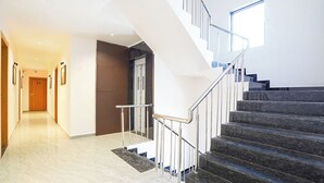 A modern hotel interior with a marble-floored hallway, a staircase with metal railings, and a door marked '105'. - Fabhotel Sahyadri Mantram (Pune)