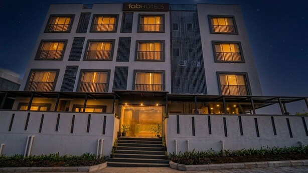 A multi-story hotel with a modern facade, illuminated windows, and a visible entrance with steps. - Fabhotel Sahyadri Mantram (Pune)