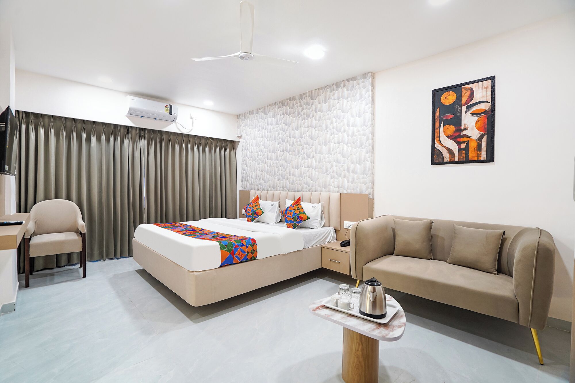 Habitació d'hotel moderna amb un llit, un sofà, una taula de treball i una taula de cafè.
