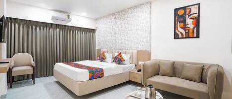 A modern hotel room with a bed, a sofa, a desk, and a coffee table.