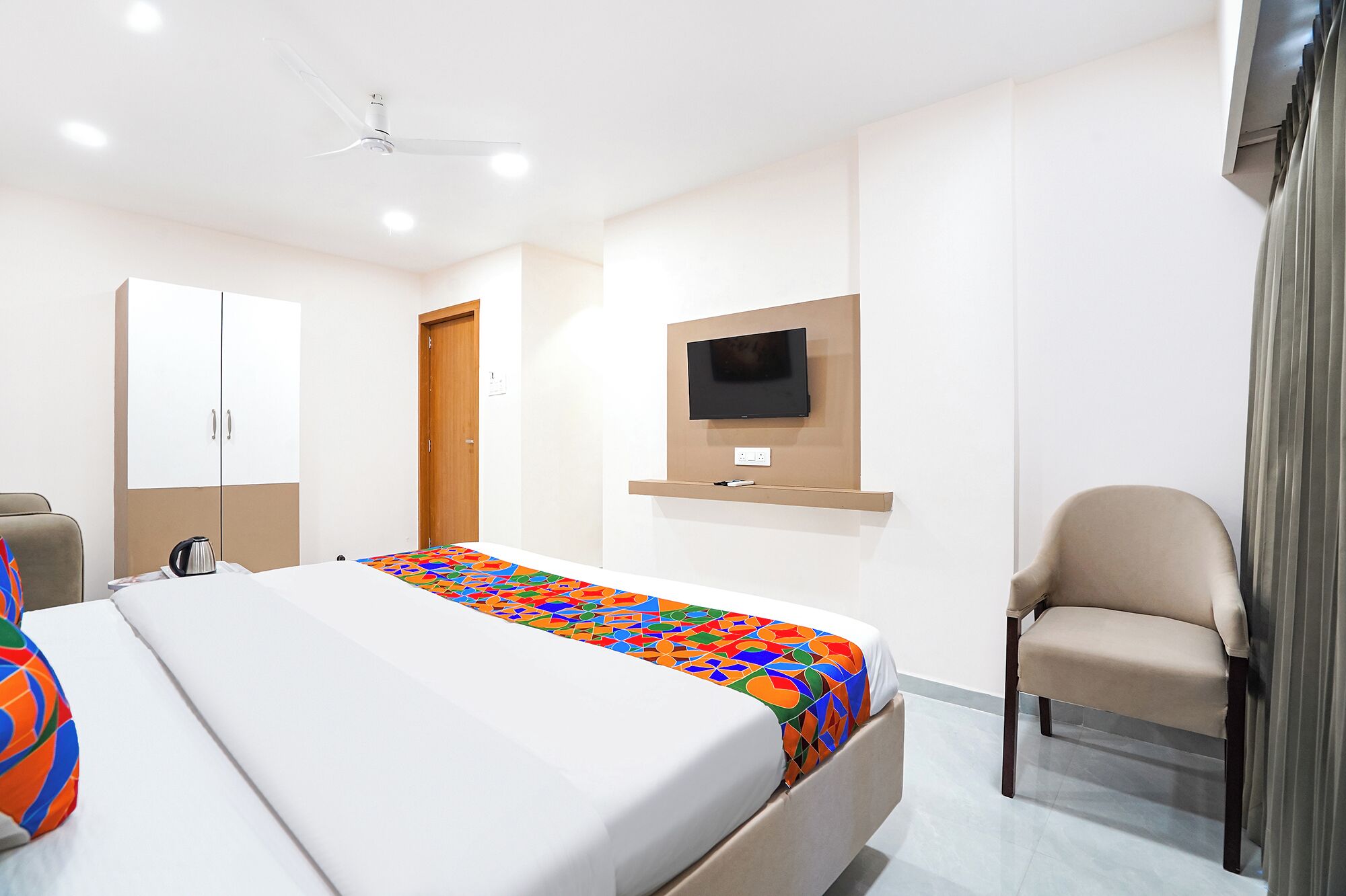 Camera d'albergo con un letto, una TV a parete, una sedia e un armadio.