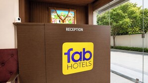 En receptionsdisk med et 'Tab Hotels' skilt, et indrammet kunstværk over disken og udsigt til en gade med træer.