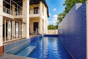 A swimming pool with blue tiles, a two-story building with balconies, and a clear sky. - FabHotel Natureâ€™s Nest In - Nr. Candolim Beach (Candolim)