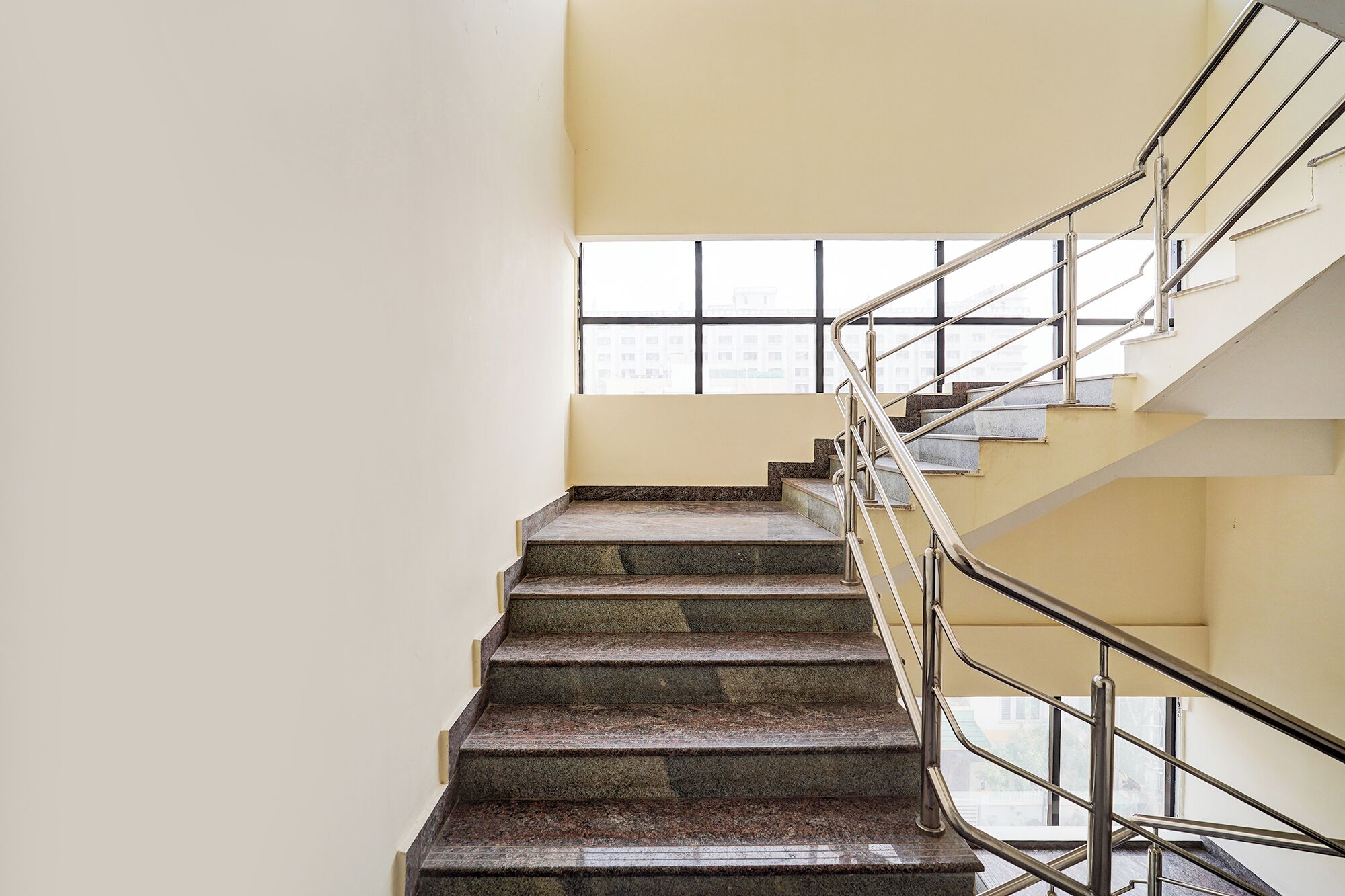 Una escalera con barandillas de metal y escalones de piedra, que conduce a un piso superior.