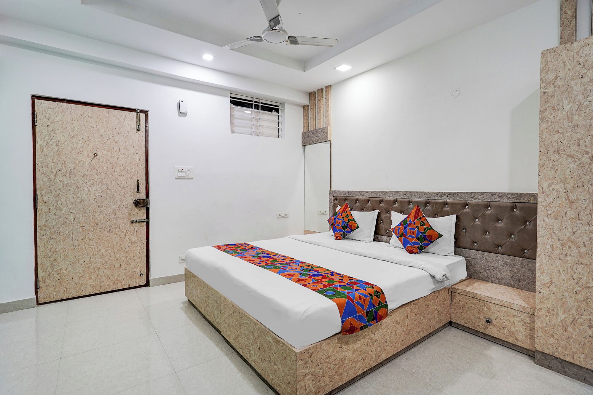 A bedroom with a bed, a headboard, a nightstand, a door, and a ceiling fan.