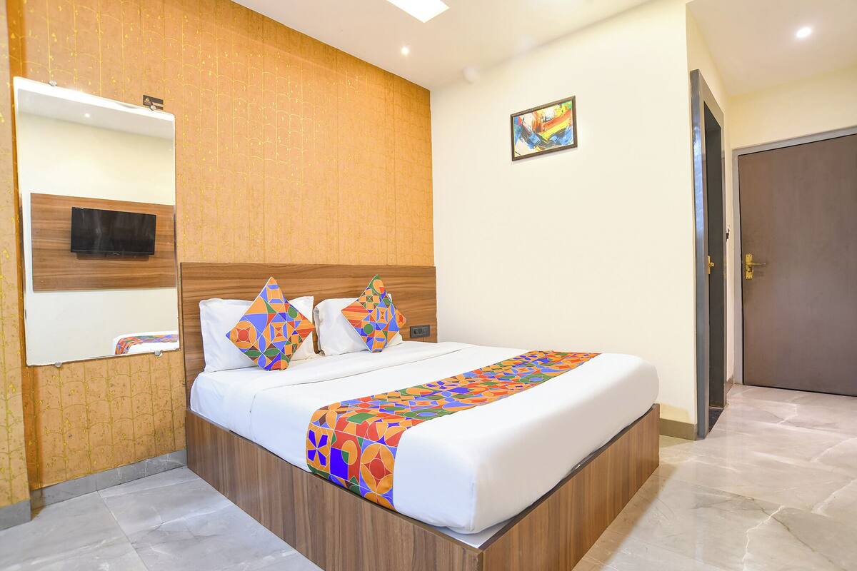 A hotel room with a bed, a television mounted on the wall, and a door.