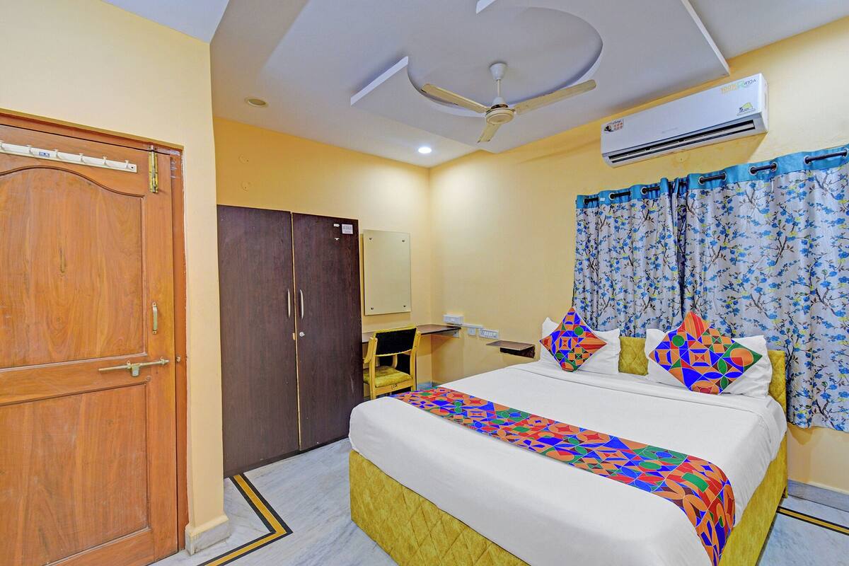 Una habitación de hotel con cama, armario, escritorio y aire acondicionado.