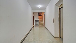 En hall med ett klinkergolv, en trädörr på höger sida och en trappa som leder upp till en övre våning.