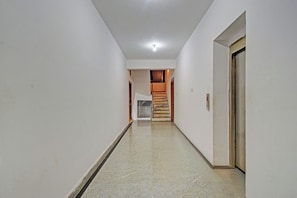 A hallway with a tiled floor, a wooden door on the right, and a staircase leading to an upper level. - FabHotel Sun Mint - Jubilee Hills (Hyderabad)