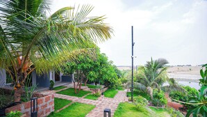 A pathway leading to a building with a view of a water body. - Fabhotel Nakshtra Resort (Tasgaon)