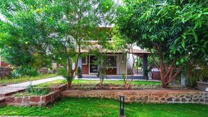 A courtyard with a brick pathway, a small garden, and a building with a tiled roof. - Fabhotel Nakshtra Resort (Tasgaon)
