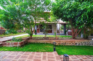 Un patio con un camino de ladrillo, un pequeño jardín y un edificio con techo de tejas.