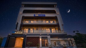 A multi-story building with a 'fab hotels' sign, a 'luxury studio' sign, and a visible crescent moon in the night sky. - FabHotel 24x Living (Gurugram)