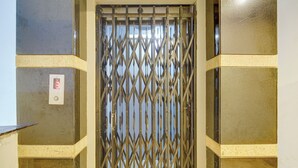 A metallic gate with a geometric pattern, a digital display, and a wall-mounted emergency light.