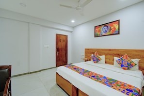 Camera da letto con una testiera in legno, un letto con cuscini decorati, una ventola a soffitto e un quadro appeso al muro.
