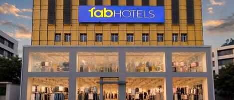 A hotel with a prominent sign reading 'fabHOTELS' and large glass windows displaying clothing.