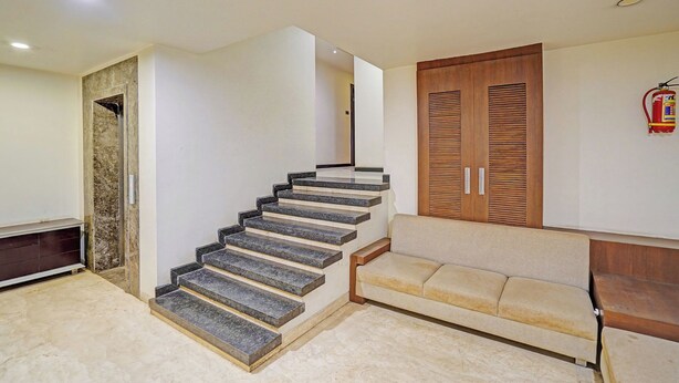 Una escalera que conduce a un segundo piso, un armario de madera y un sofá color beige en un interior moderno.