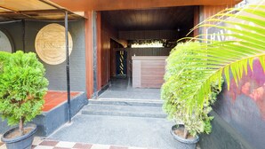 Entrada d'hotel amb una recepció, unes escales i plantes en testos.