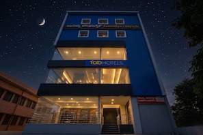 A modern building with a sign for 'fabHOTELS' and 'SAANIDHYA COMFORTS' indicating a hotel. - FabHotel Saanidhya Comforts - Tumkur Road (Kunigal)