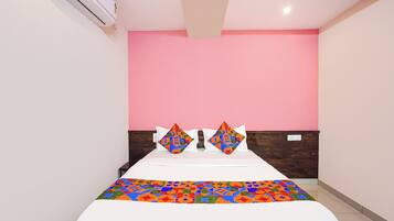 A hotel room with a bed, a pink wall, and a wooden headboard.