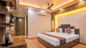 Quarto de hotel com cama, mesa de cabeceira e ventilador de teto.