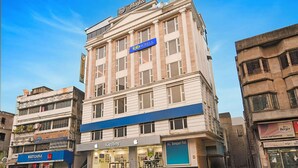 Um edifício de vários andares com uma placa azul para 'Fab Hotels' no segundo andar, uma loja Apple no andar térreo e uma loja 'Kutchna' à esquerda.