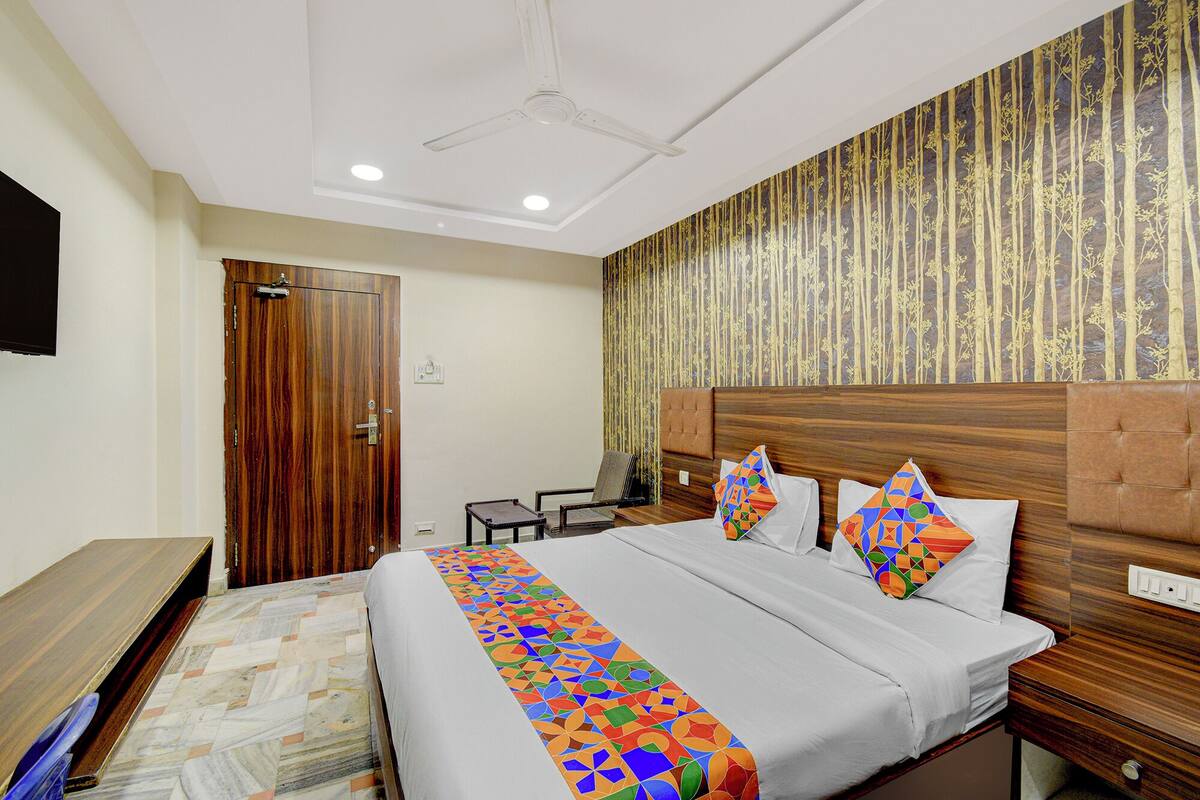 A hotel room with a bed, a desk, a chair, and a wardrobe.