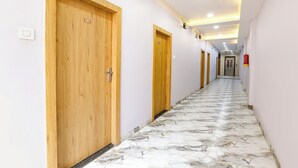 A hotel hallway with wooden doors, numbered signs, and a marble floor. - FabHotel Suraj Palace (Indore)