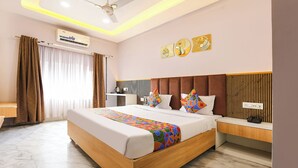 A hotel room with a bed, bedside table, and a wall-mounted air conditioner. - FabHotel Suraj Palace (Indore)