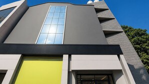A modern building with a prominent vertical window, a yellow facade, and a staircase leading to an entrance. - Fabhotel Moro Gujranwala Town (New Delhi)