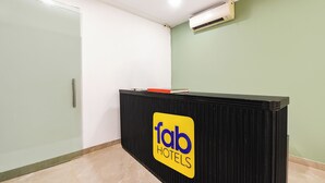 A reception desk with a 'fab hotels' sign, a glass door, and an air conditioning unit on the wall. - Fabhotel Moro Gujranwala Town (New Delhi)