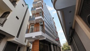 Un hotel de varios pisos con balcones, unidades de aire acondicionado y un letrero que indica que es un hotel y residencia real.