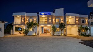 Een modern hotel met een plat dak, een bord en een geplaveid entreegebied.