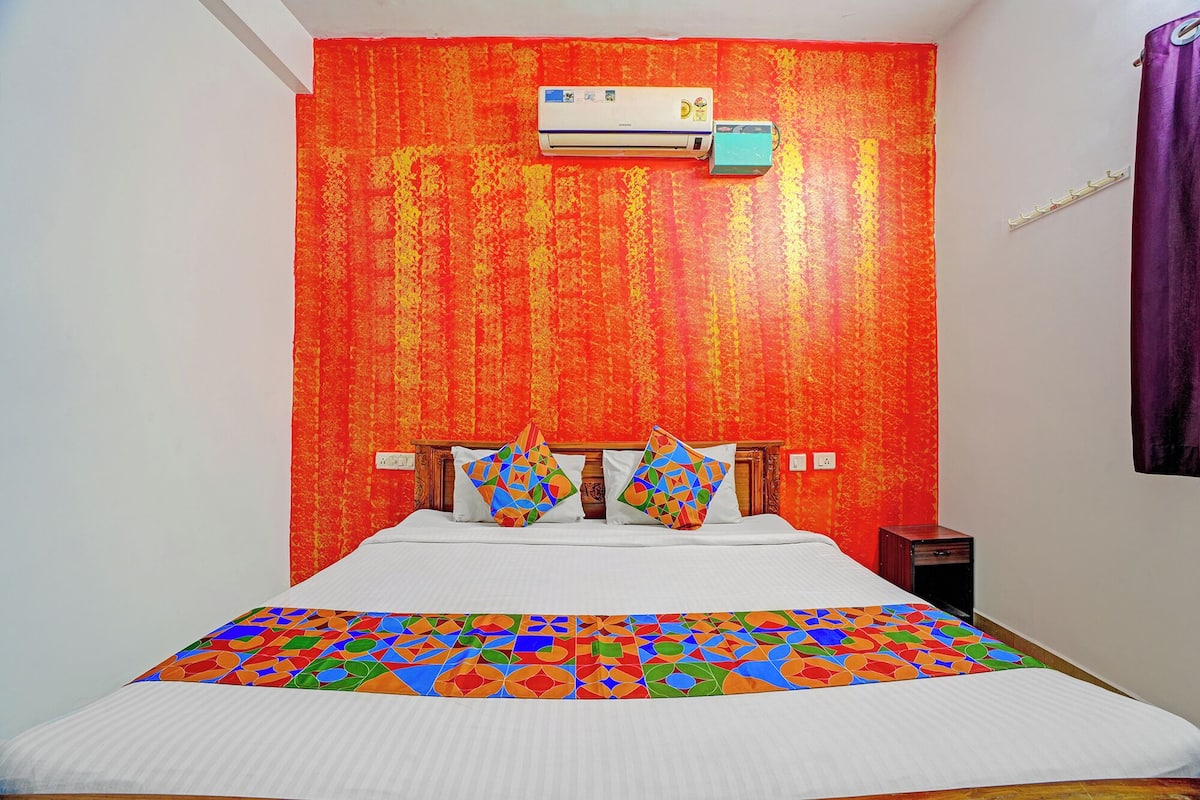 A room with a bed, an air conditioner, and a patterned bedspread.