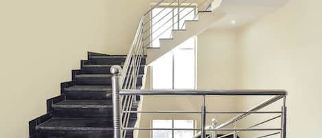 A staircase with black steps and a metal railing, leading to an upper floor.