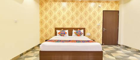 A bedroom with a bed, patterned wallpaper, a ceiling fan, and a geometric-patterned floor.