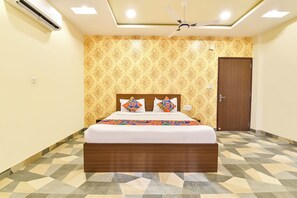 A bedroom with a bed, patterned wallpaper, a ceiling fan, and a geometric-patterned floor. - Fabhotel Shivalika (Jaipur)