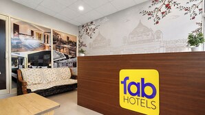 Ett väntrum med en soffa, ett träbord och en vägg med en skylt som visar namnet på hotellet.