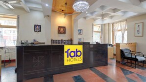 A hotel reception area with a modern design, including a reception desk, ceiling fans, and a chandelier.