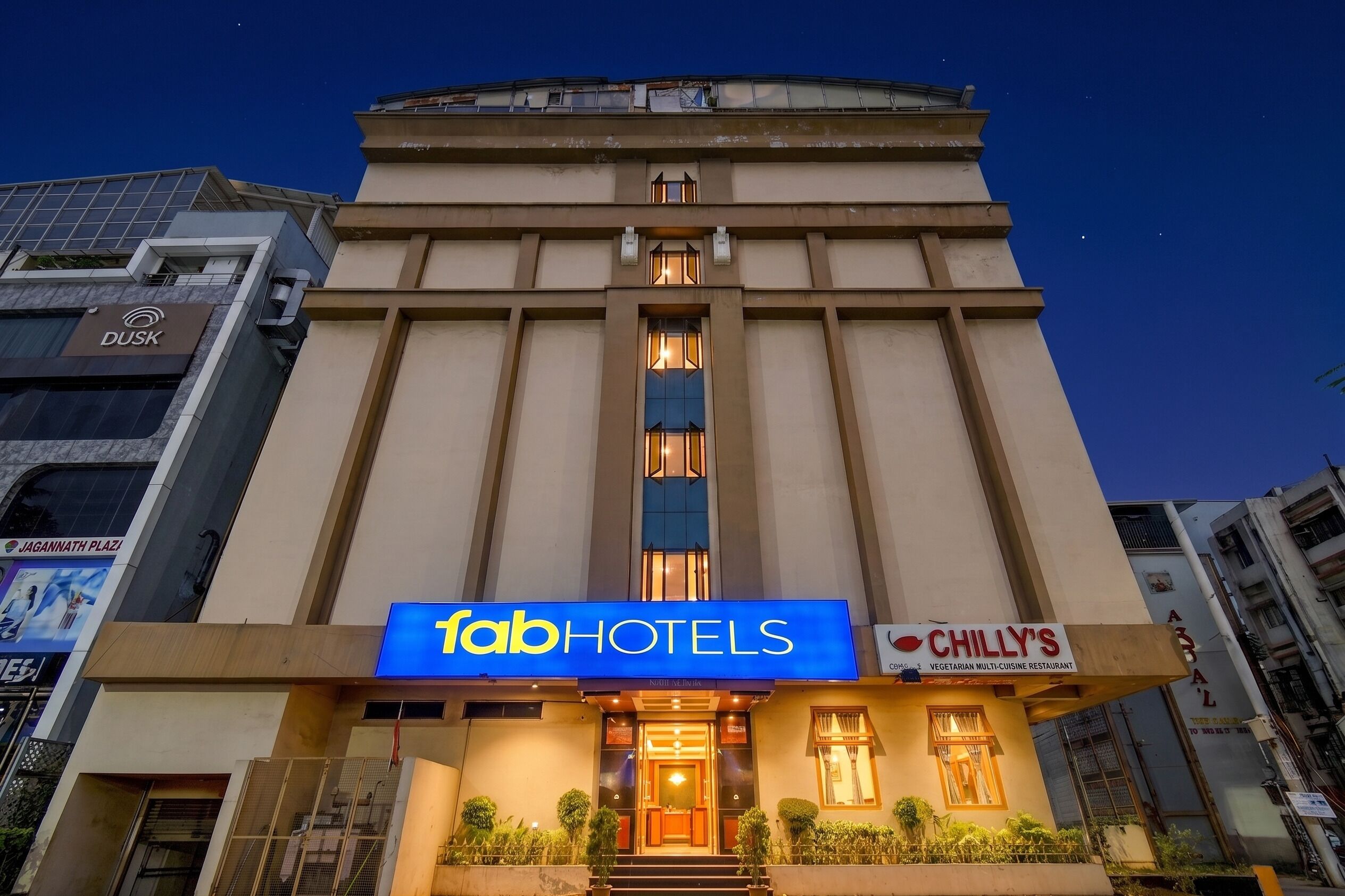 Un bâtiment sur lequel on peut voir une enseigne pour la chaîne d’hôtels « Fab Hotels » et le restaurant « Chilly’s ».