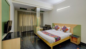A hotel room with a bed, a desk, a chair, a television, and a curtain.